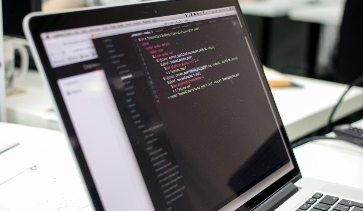 Programmerare som arbetar vid dator med kod på skärmen